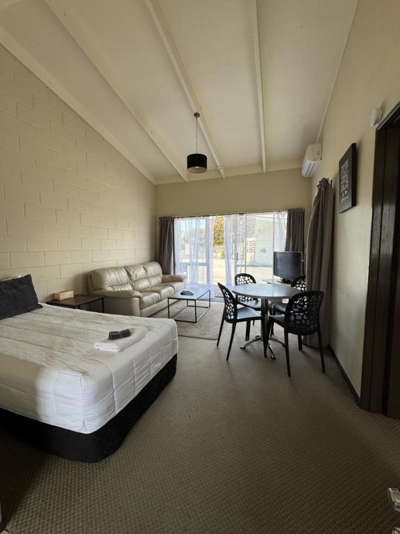 a hotel room with a bed and a table and chairs at Fountain Court Motel in Tauranga