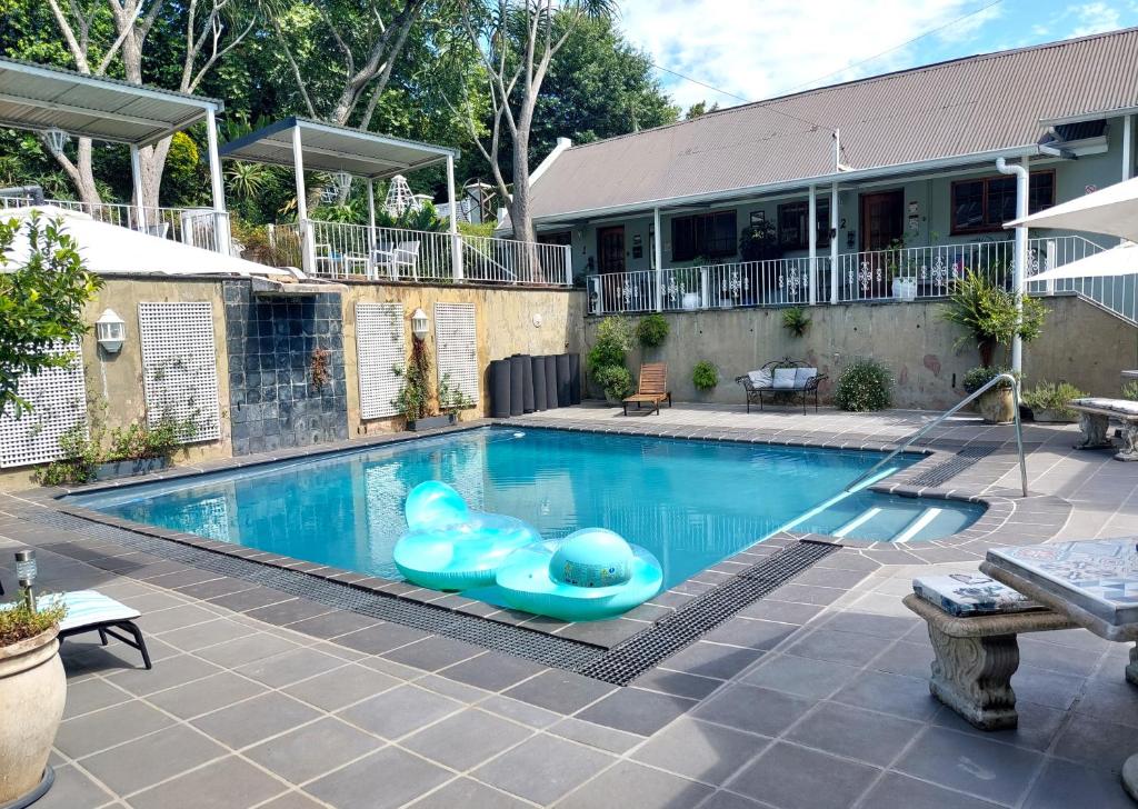 a swimming pool with an inflatable pool toy in front of a house at Apartment 7 On Oakleigh in Pietermaritzburg