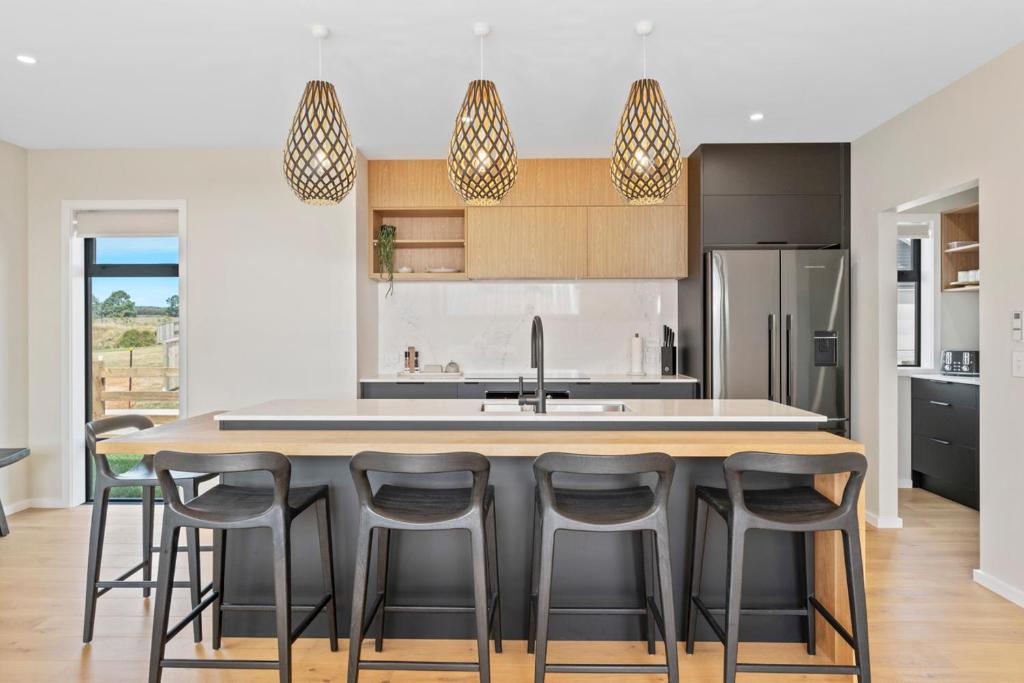 a kitchen with a large island with bar stools at Wharewaka Escape - Taupo in Taupo
