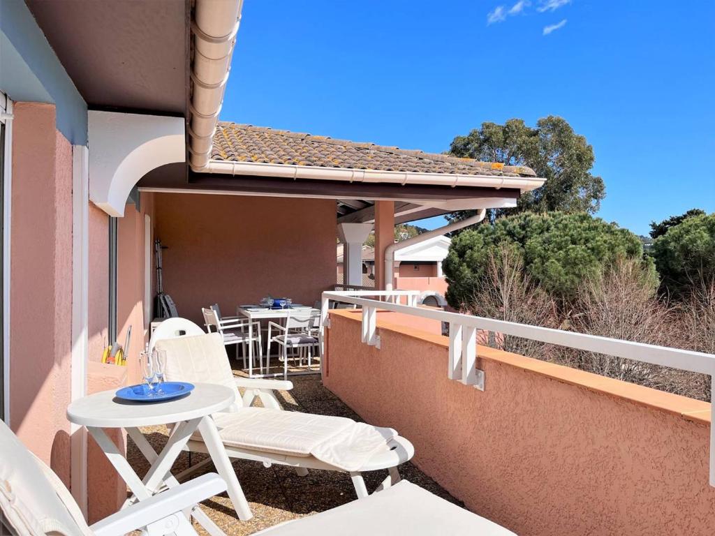 d'une terrasse avec des chaises blanches et une table sur un balcon. dans l'établissement Appt climatisé 3 pièces - 6 pers - Terrasse, parking à 200m de la plage - FR-1-251-845, au Lavandou