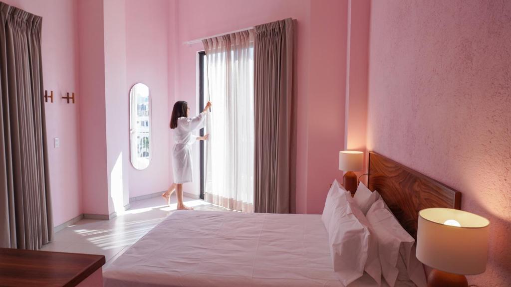 Uma mulher de vestido branco está a olhar pela janela. em Hotel Tepalcates em San Patricio Melaque