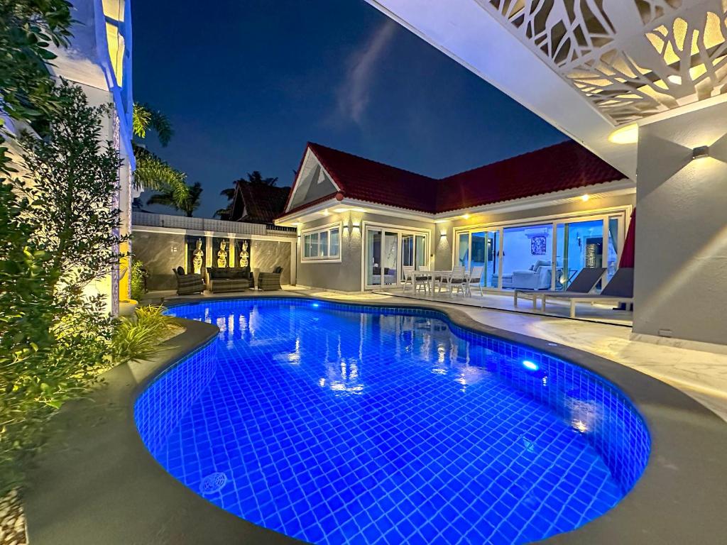 乔木提恩海滩VIEW TALAY VILLAs POOL 67, JOMTIEN BEACH, PATTAYA的夜晚房子前的游泳池
