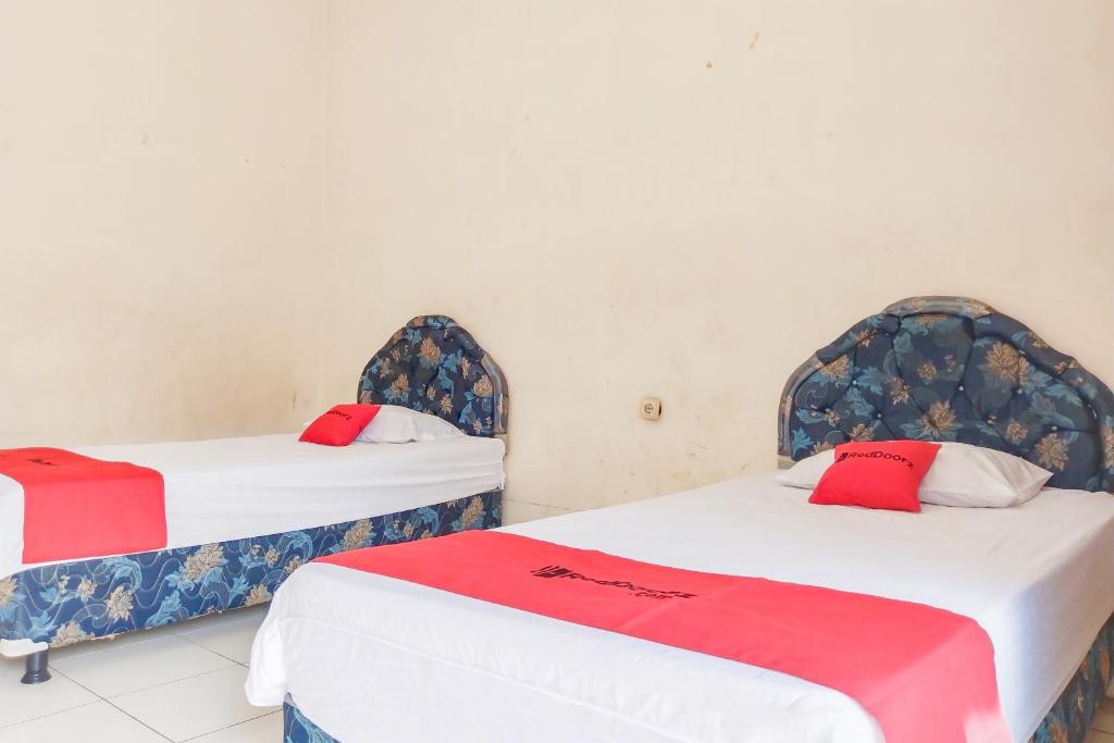 two beds with red pillows in a room at RedDoorz at Hotel Padjajaran Tasikmalaya in Tasikmalaya
