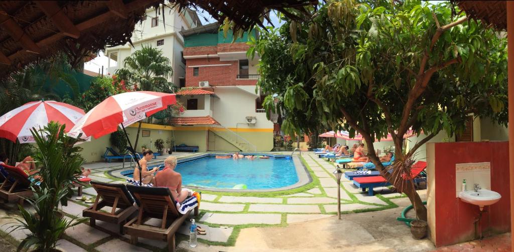 een groep mensen die rond een zwembad zitten bij Hotel Thushara in Kovalam
