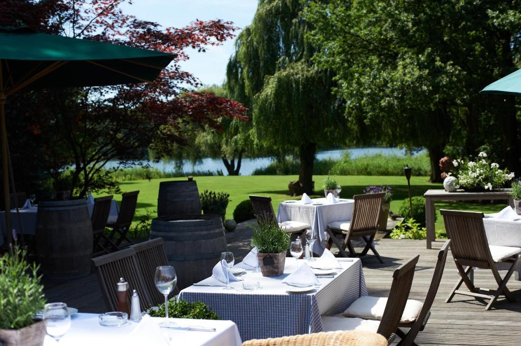 ein Restaurant mit Tischen und Stühlen und Seeblick in der Unterkunft Landhaus am See in Garbsen