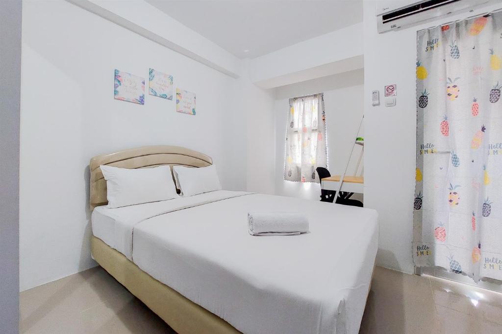 タンゲランにあるFancy and Nice Studio at Urbantown Serpong Apartment By Travelioの大きな白いベッドと窓のある白い寝室