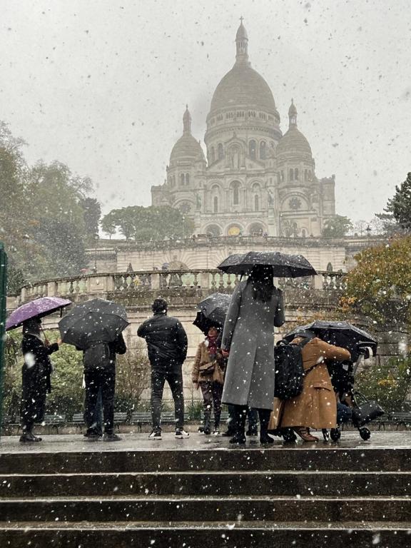 des personnes marchant dans les escaliers dans la neige avec des parapluies dans l'établissement Montmartre joli 2 pièces au pied du Sacré Coeur, à Paris