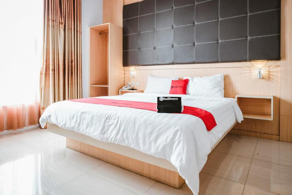 a bedroom with a large bed with a black headboard at RedDoorz Premium at Hotel T-ONE Jambi in Tanjungjohor