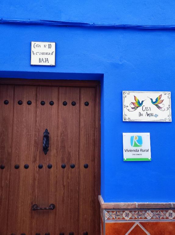a blue wall with a wooden door and a sign at Casa Due Amori in Montilla