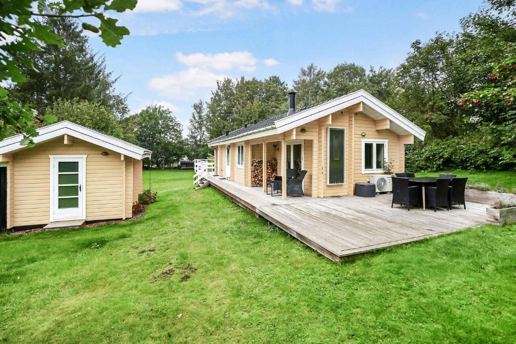 Una pequeña casa con una terraza de madera en el patio. en The Sun House, en Hundested
