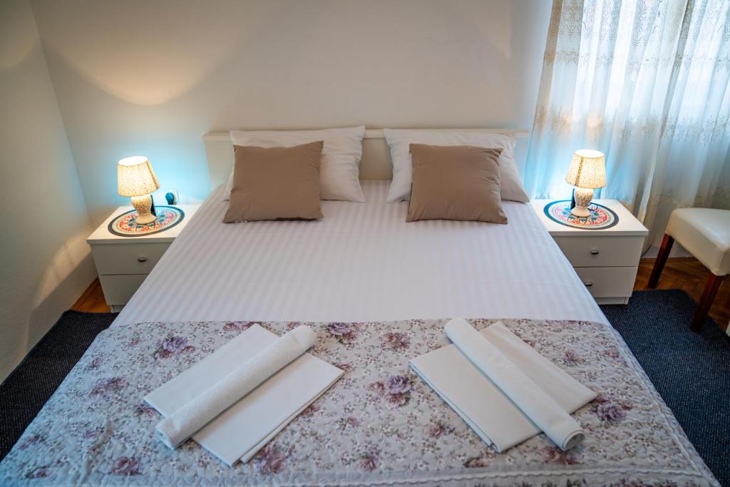 a bedroom with a large white bed with two lamps at Guest House Cesic in Dubrovnik