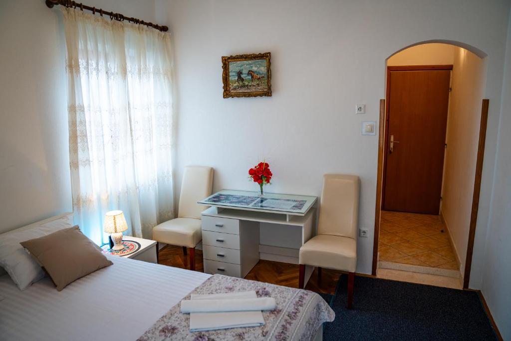 a bedroom with a bed and a desk with a flower on it at Guest House Cesic in Dubrovnik