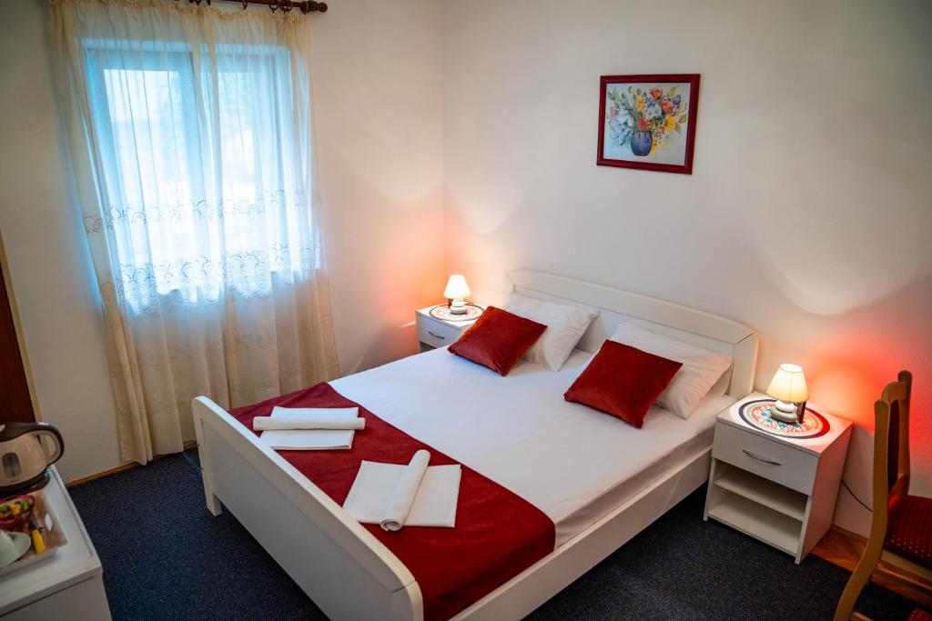 a bedroom with a large white bed with red pillows at Guest House Cesic in Dubrovnik
