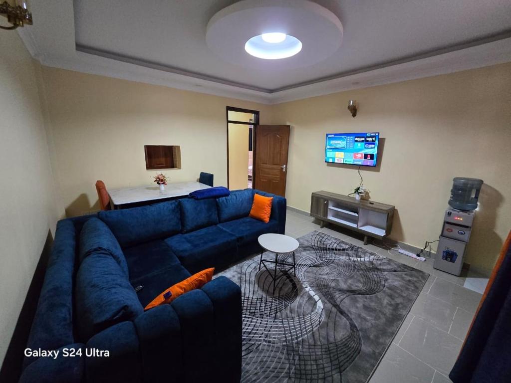 a living room with a blue couch and a tv at The comfort 2 bedrooms pioneer in Eldoret