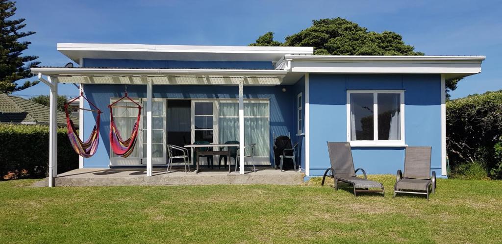 帕拉帕拉乌穆Kapiti Seaside Magic的庭院里带桌椅的蓝色房子