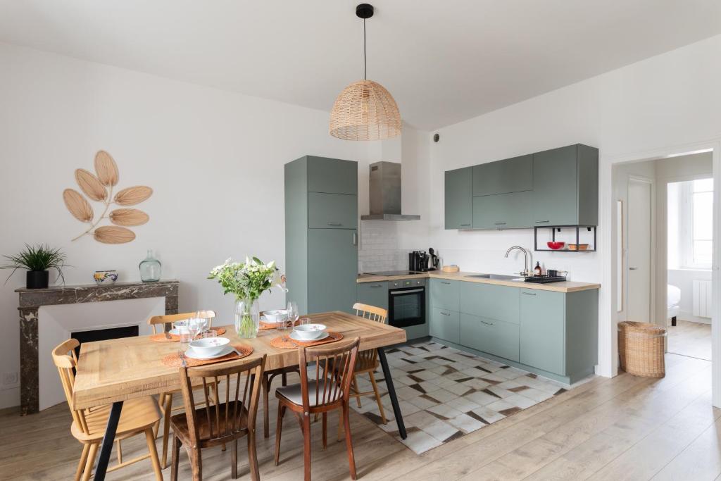 une cuisine et une salle à manger avec une table et des chaises en bois dans l'établissement Coquillages et Crustacés - Apt avec balcon vue mer, à Saint-Malo
