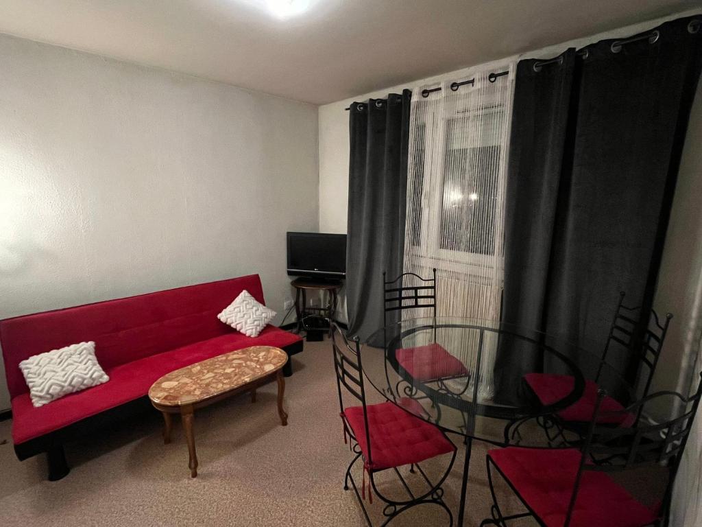 un salon avec un canapé rouge et une table en verre dans l'établissement Villeurbanne parc tête d or, à Villeurbanne