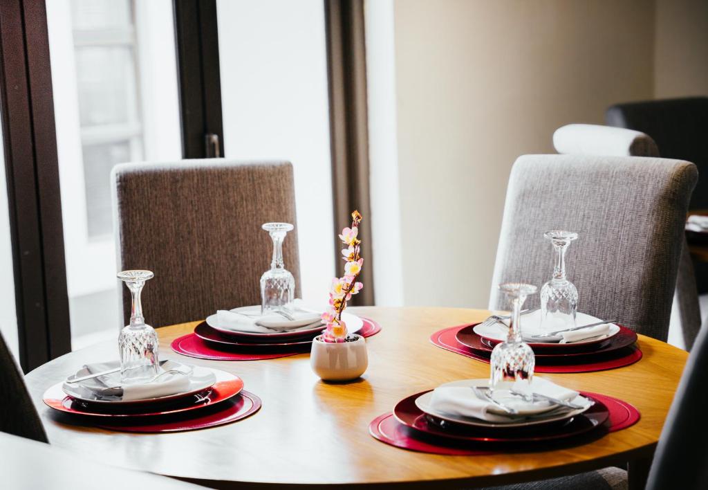 a wooden table with plates and wine glasses on it at Ehrlichpark Lodge self catering and spa in Bloemfontein