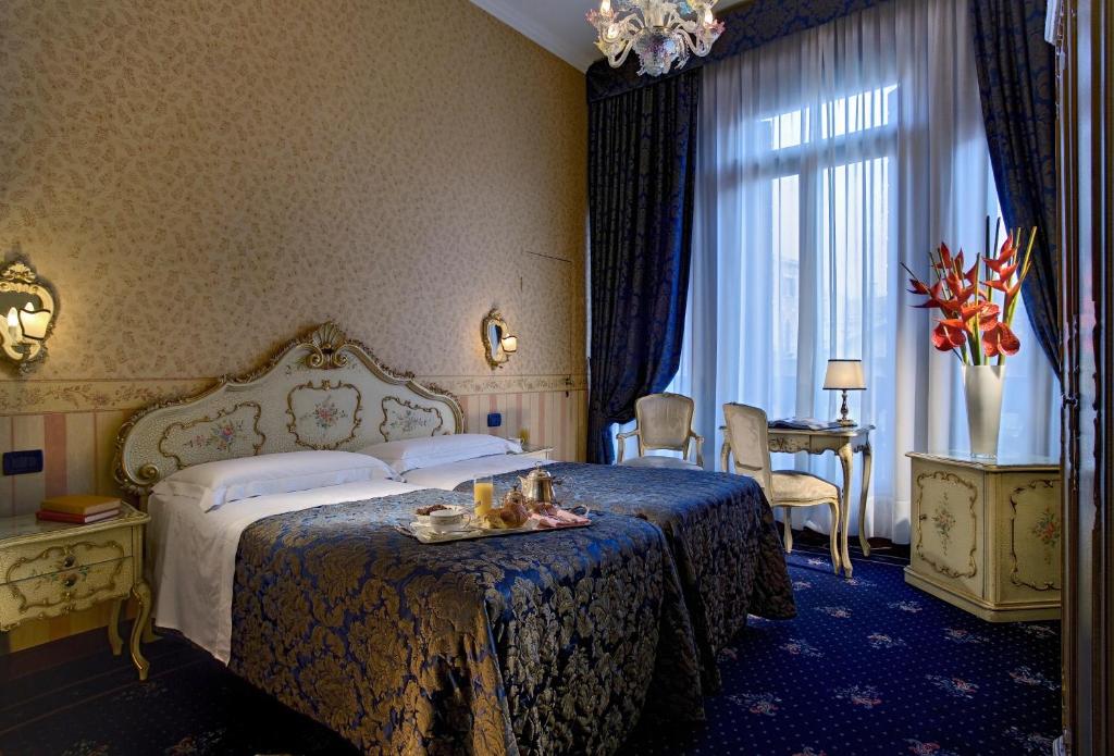 a hotel room with a bed, table and window at Hotel Montecarlo in Venice