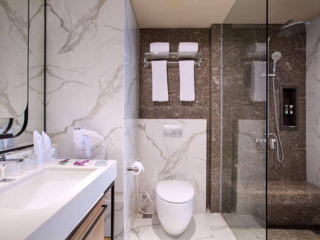 a bathroom with a toilet and a sink and a shower at Mercure Jakarta Batavia in Jakarta
