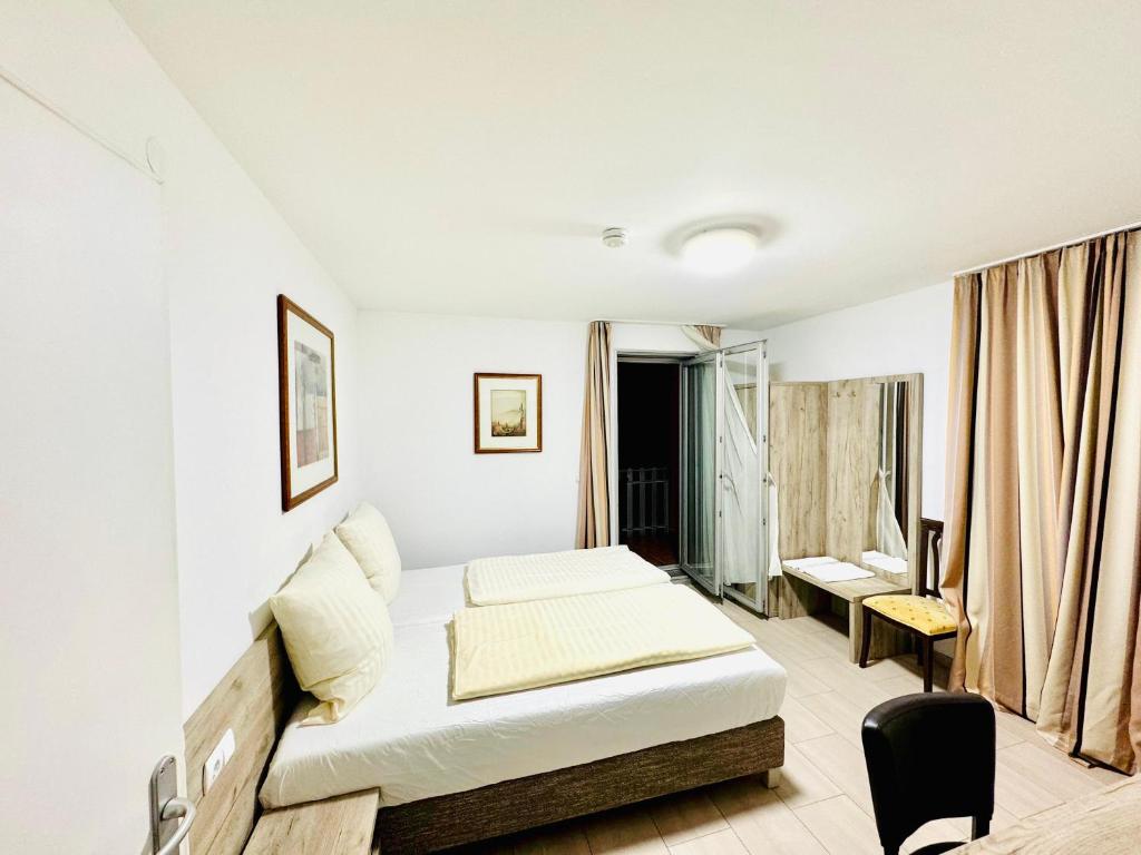 a white bedroom with a bed and a desk at Hotel Soad in Salach