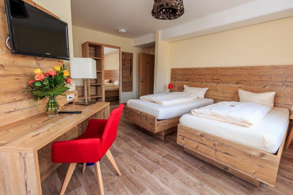 een hotelkamer met 2 bedden en een rode stoel bij Landhotel Gary in Wolframs-Eschenbach