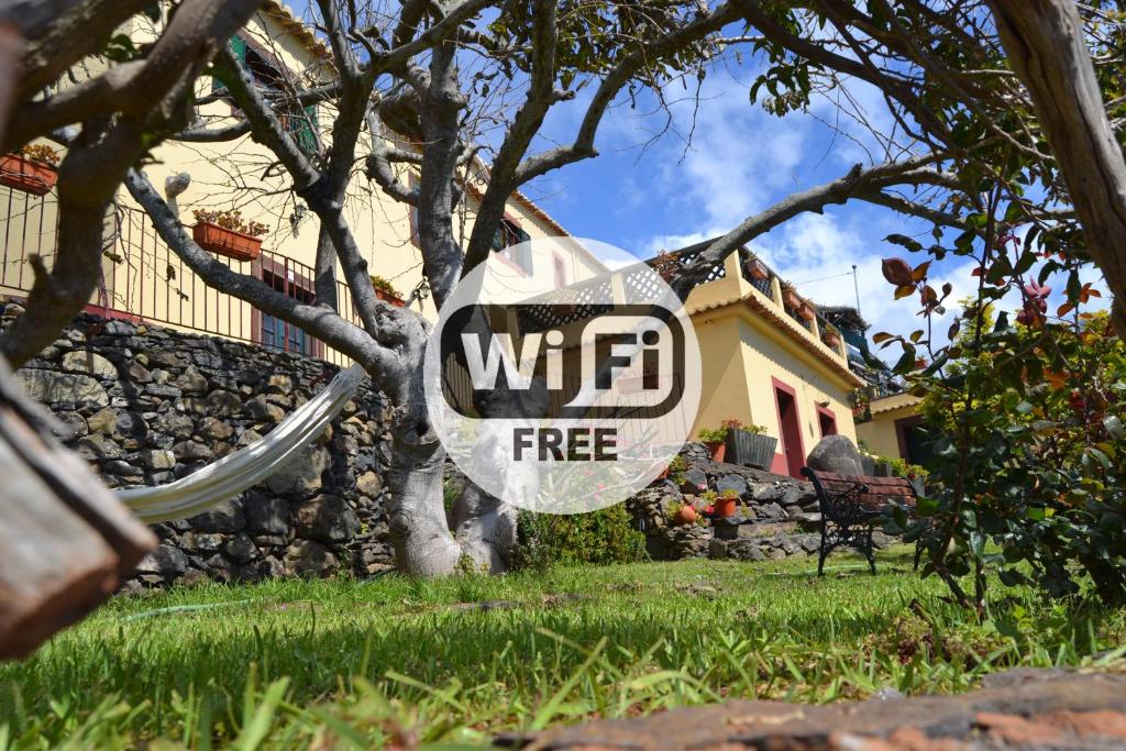 a sign on a tree in front of a house at Casal São João Cottages in Fajã da Ovelha