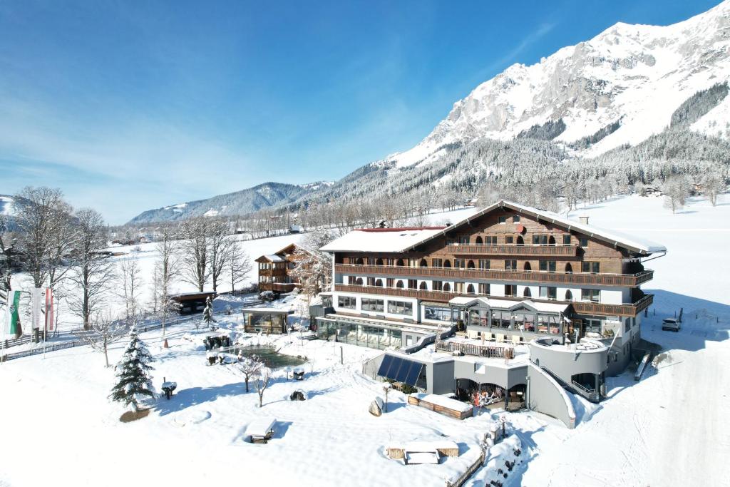 un hotel nella neve tra le montagne di Hotel Berghof a Ramsau am Dachstein