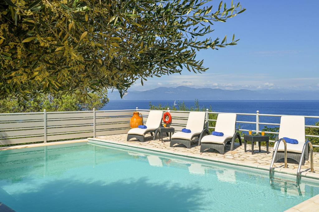 a group of chairs sitting next to a swimming pool at Lioniskari Seaviews - Paxoi's Private Pool Oasis in Porto Ozias