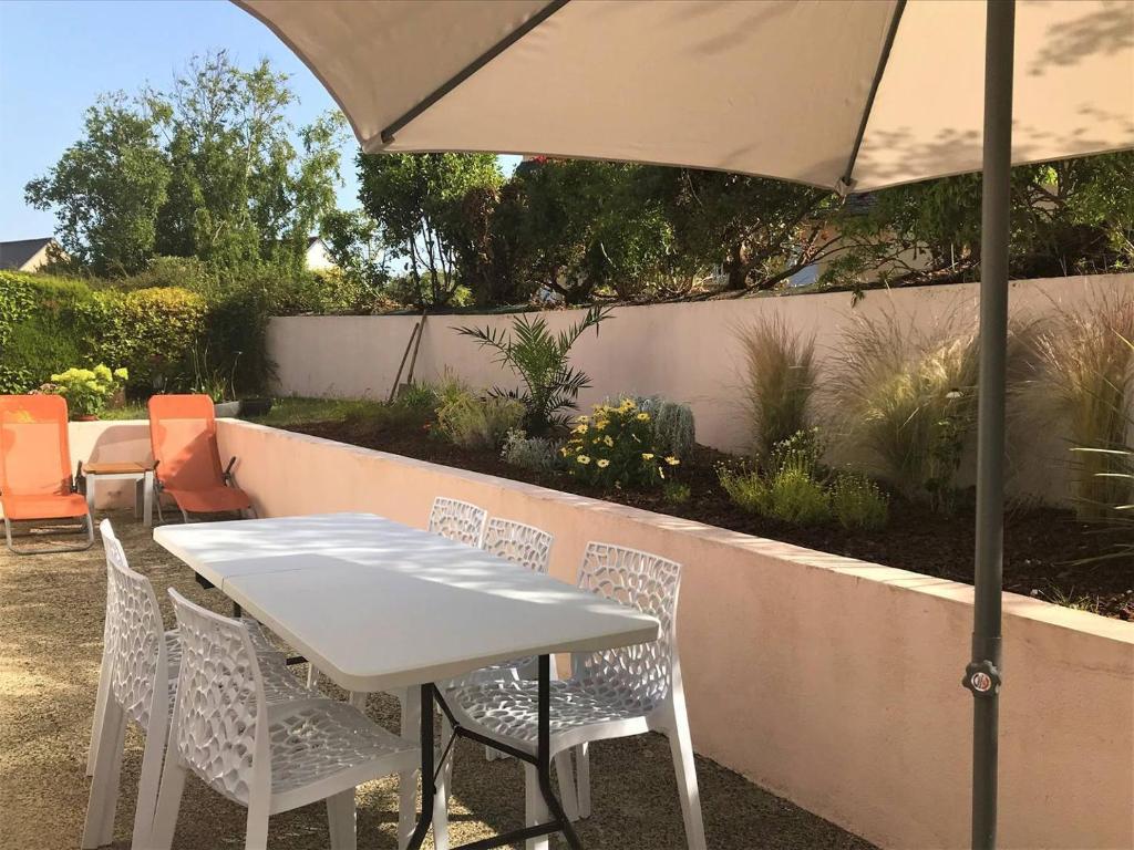 une table et des chaises blanches sous un parasol dans l'établissement Maison avec jardin, WIFI à 600m de la mer à TREGASTEL - Réf 58, à Trégastel