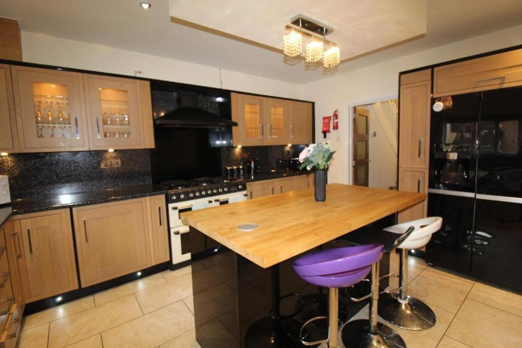 Una cocina con una mesa de madera con taburetes de bar morados. en Ridge House, en Rotherham Road