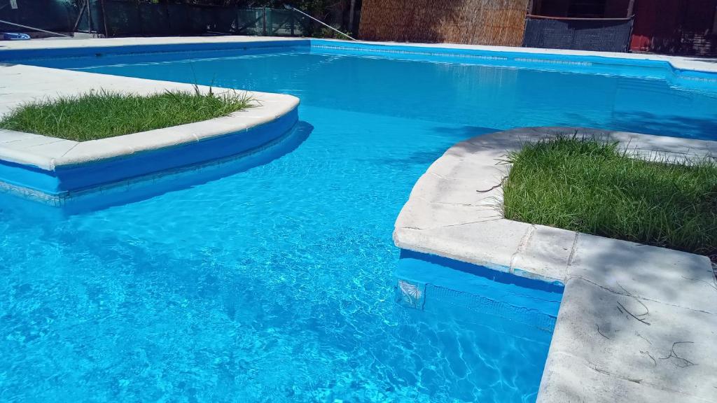 a swimming pool with blue water and grass in it at JONATAN II Bed & Breakfast in Mina Clavero