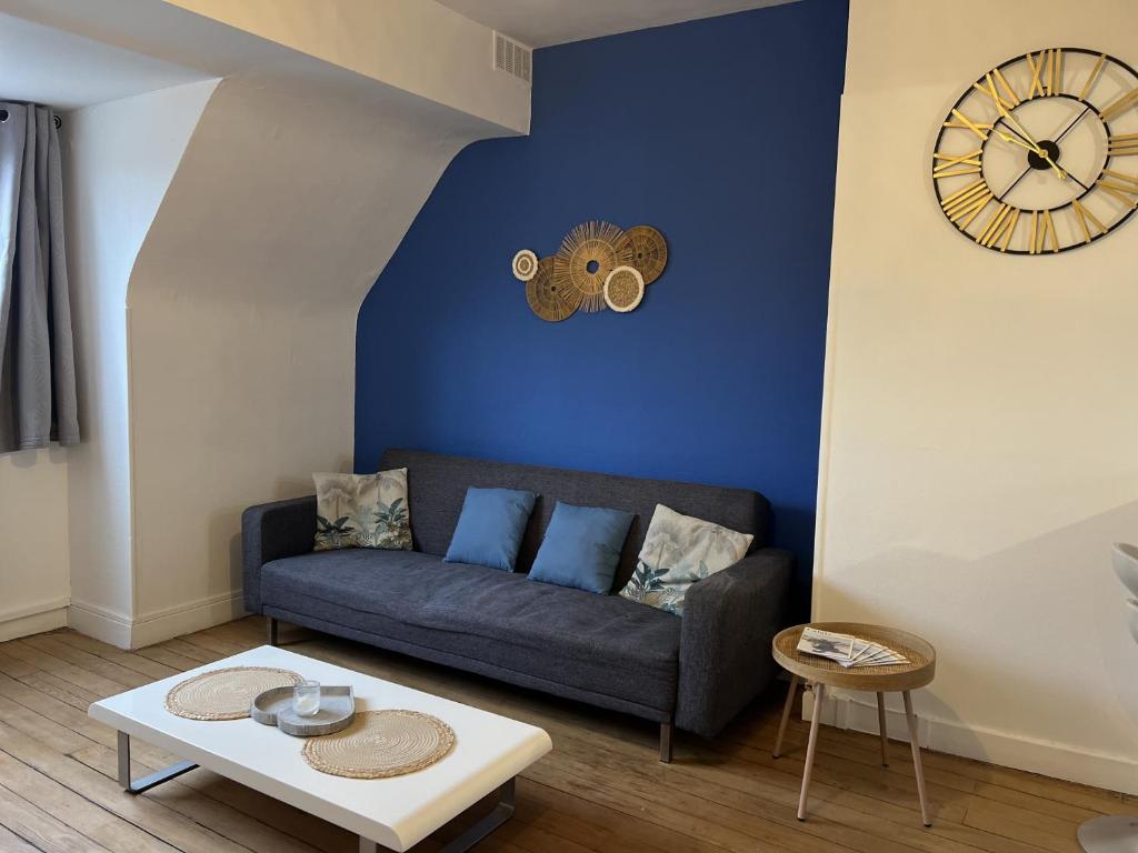 un salon avec un canapé et une horloge au mur dans l'établissement Au cocon bleu, à Calais