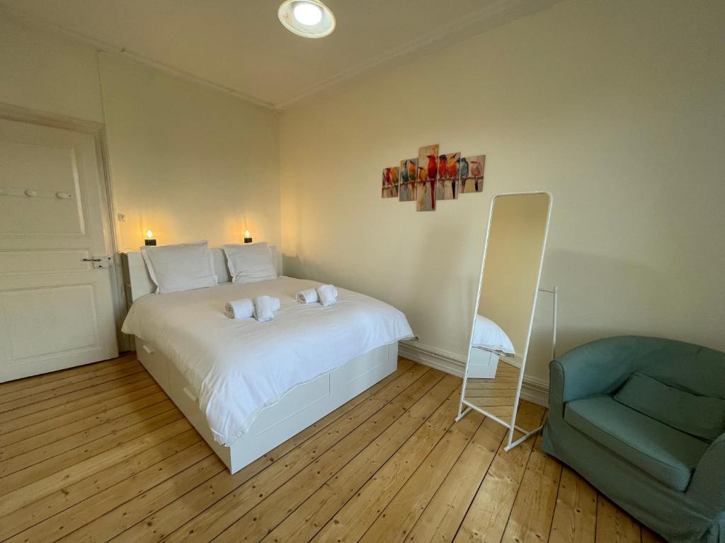 une chambre avec un lit blanc et une chaise bleue dans l'établissement Le Kablé - Proche Palais de la Musique et des Congrès - Lycée Kléber, à Strasbourg