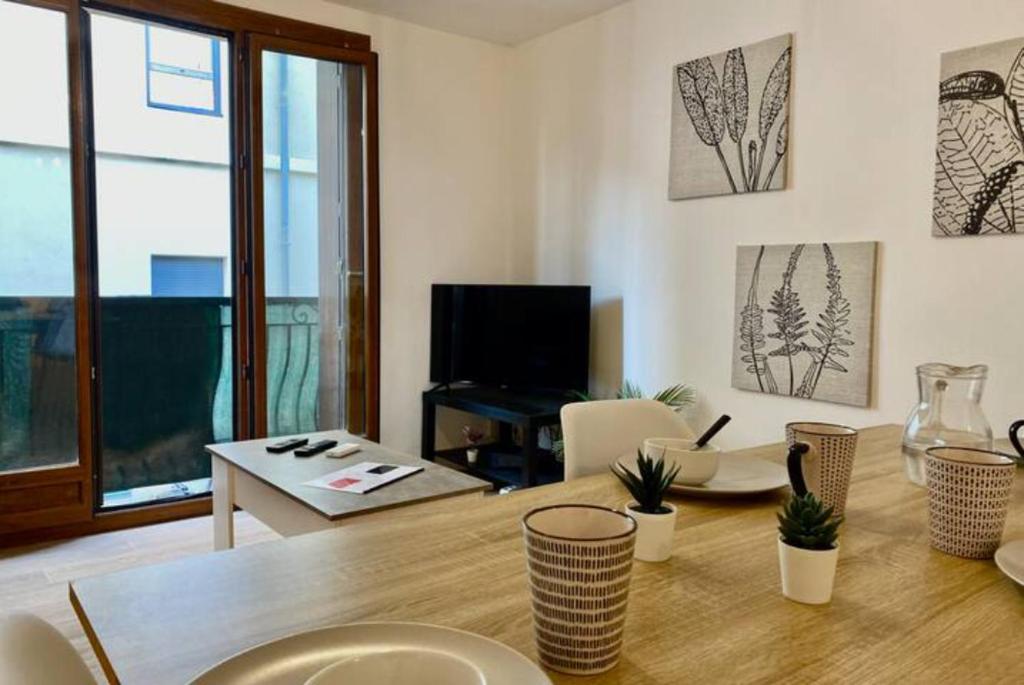 un salon avec une table en bois et une télévision dans l'établissement Le carmen - terrase - garage - clim, à Nîmes