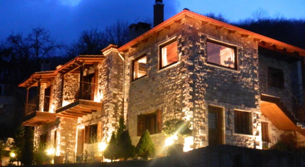 una casa de piedra con luces encendidas por la noche en Petrino Rodo, en Karpenisi