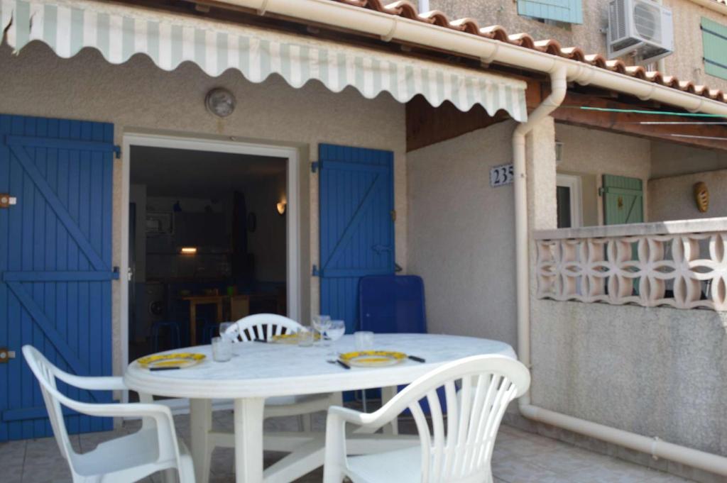 une table et des chaises blanches assises sur un balcon dans l'établissement NP140-235 Pavillon 3 pièces, 2 chambres Narbonne Plage, à Narbonne-Plage