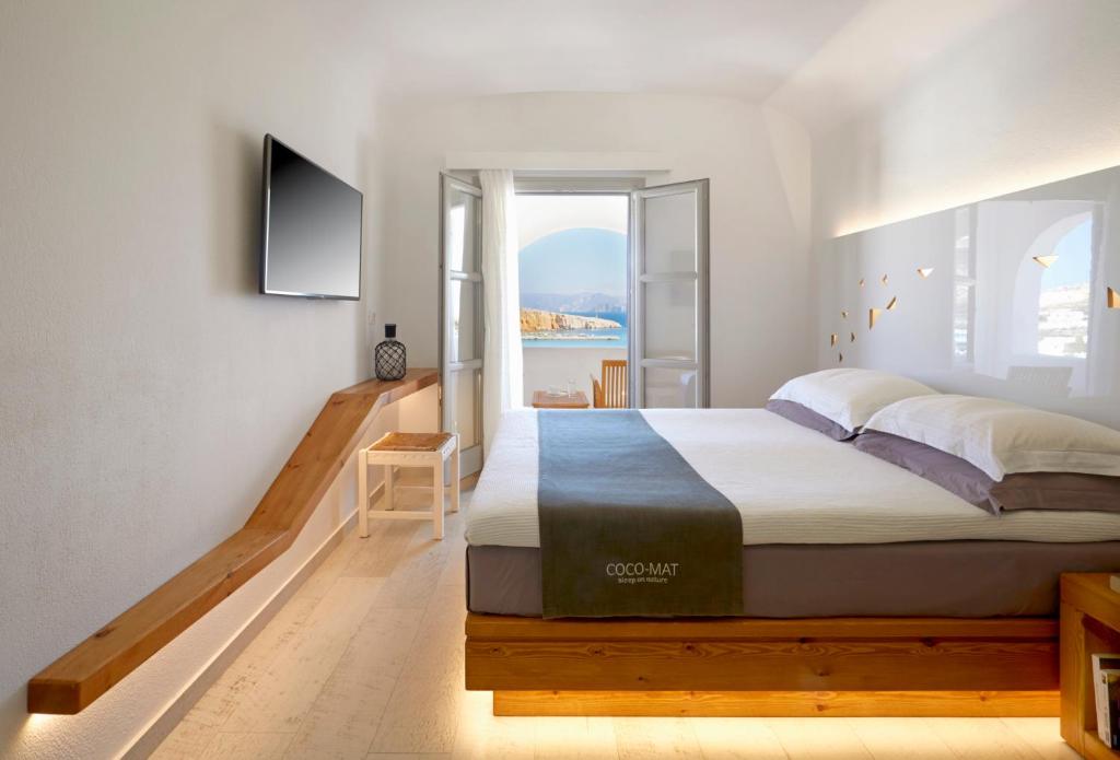 a bedroom with a large bed and a window at Vrahos Boutique Hotel in Karavostasi