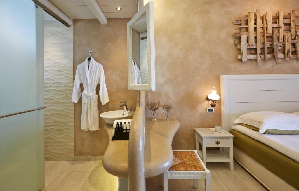 a bathroom with a sink and a bedroom with a bed at Vrahos Boutique Hotel in Karavostasi