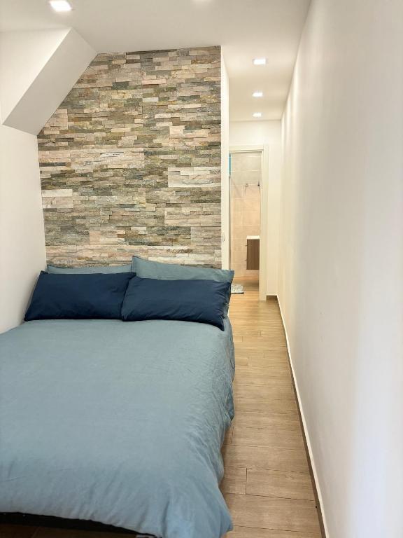 a bedroom with a blue bed with a brick wall at La Suite da Esther in Adrano