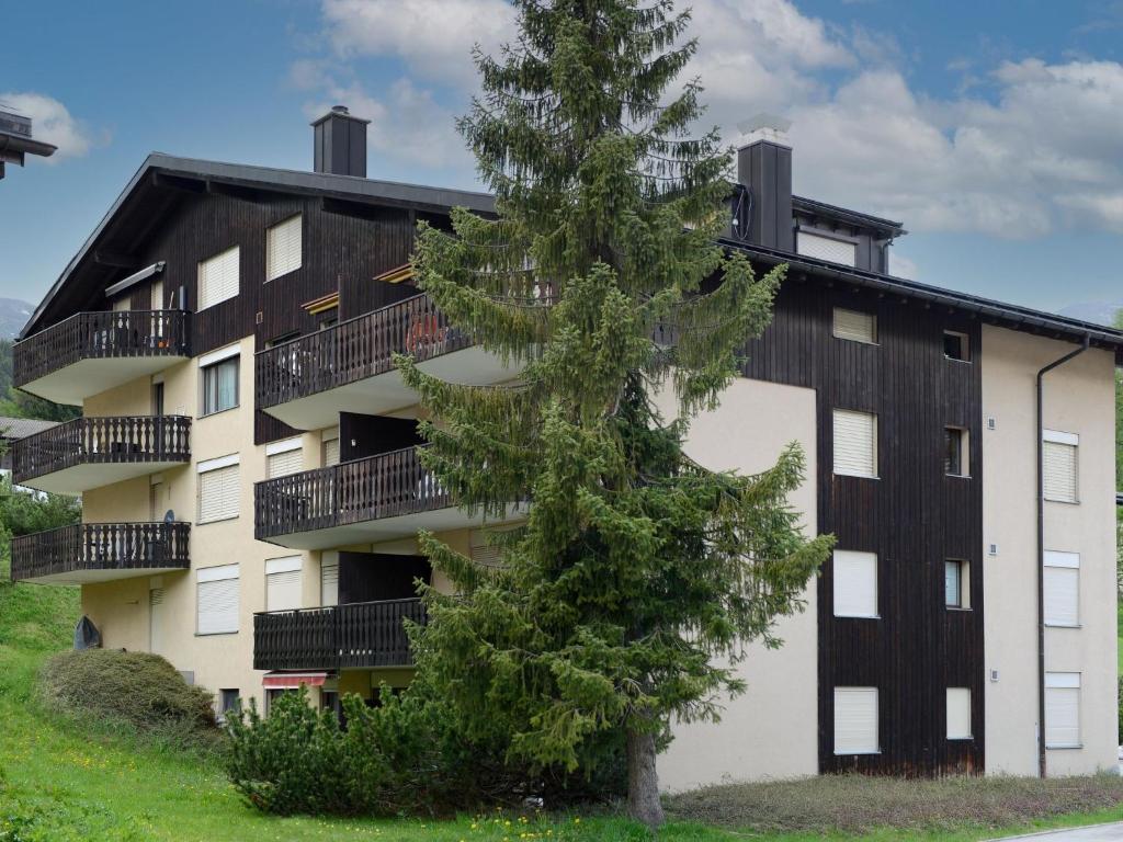 Un edificio de apartamentos con un árbol delante. en Apartment A301 by Interhome, en Lenzerheide