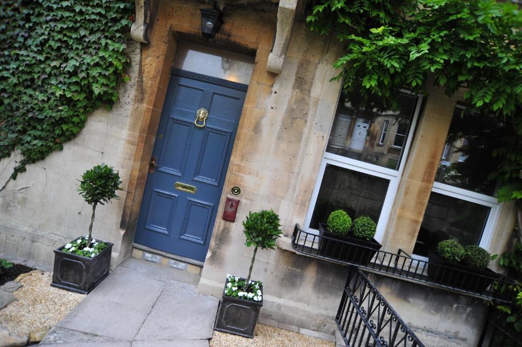 a blue door on the side of a building with potted plants at Brindleys in Bath