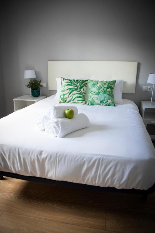 a white bed with a green apple on top of it at Playa del Silencio 2 in Castañeras