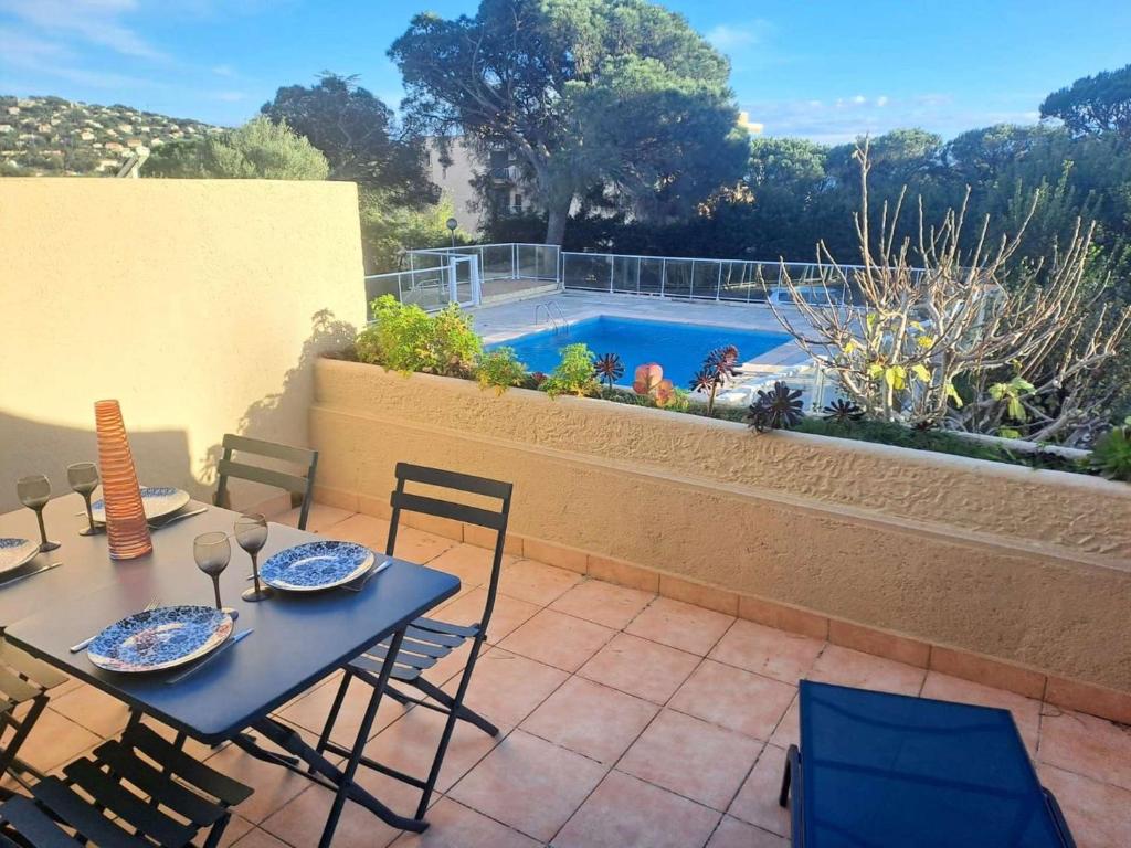 un patio avec une table et des chaises et une piscine dans l'établissement Les Virgiles Ste-Maxime, appt climatisé pour 4 pers avec vue sur la piscine, parking, à Sainte-Maxime