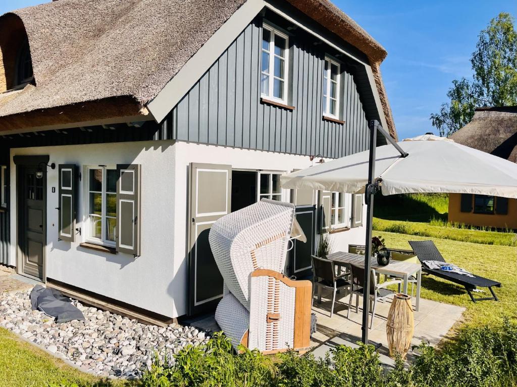 a cottage with a patio and an umbrella at Ferienhaus Küstenkind Feriendorf 08 Klein Stresow Rügen by ruyastay in Putbus