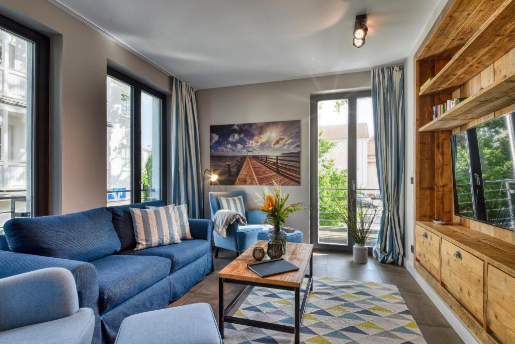 ein Wohnzimmer mit blauen Möbeln und großen Fenstern in der Unterkunft Ferienwohnung Reetkoje in der Villa Martha Binz in Binz