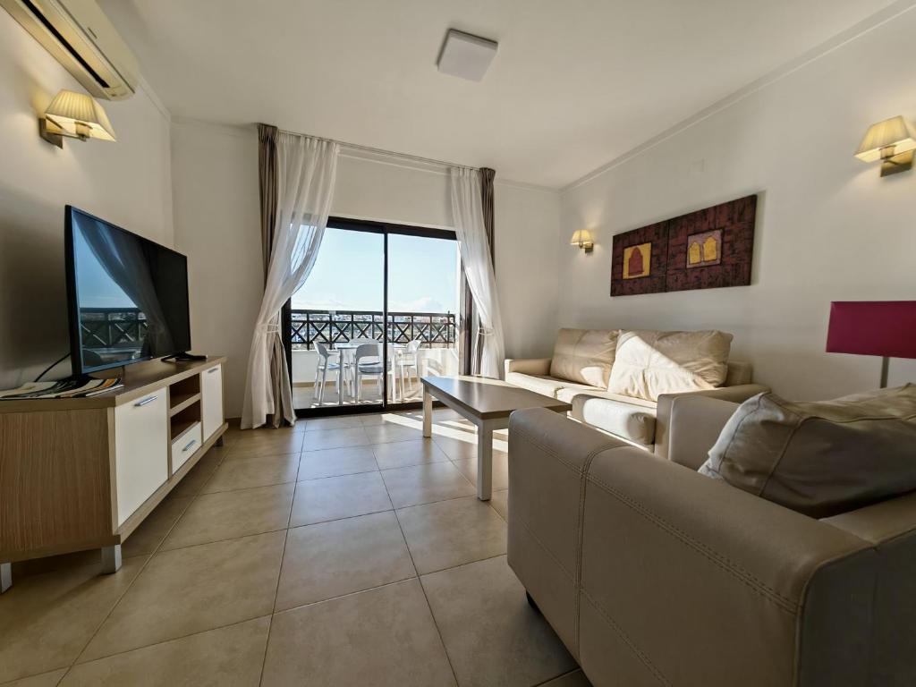 a living room with a couch and a television at Sagres Time Apartamentos in Sagres