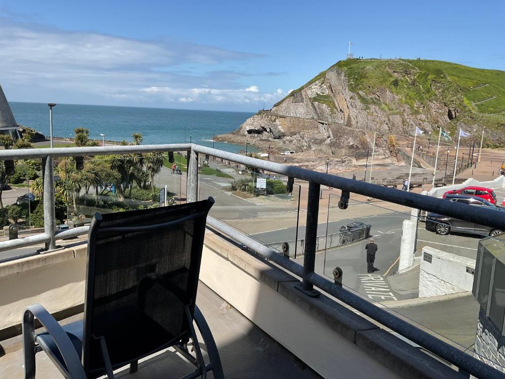 una silla sentada en un balcón con vistas al océano en 2 Bed Ilfracombe Seafront Apartment with stunning views, en Ilfracombe