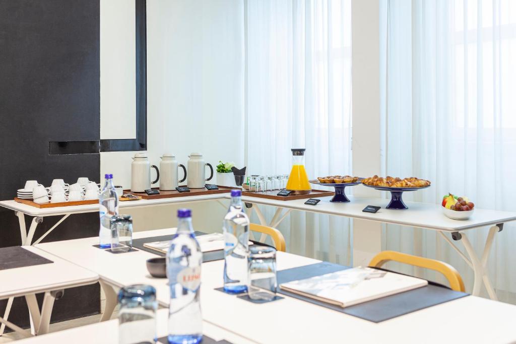 A bright breakfast or meeting room laid out with pastries, fruit and drinks.
