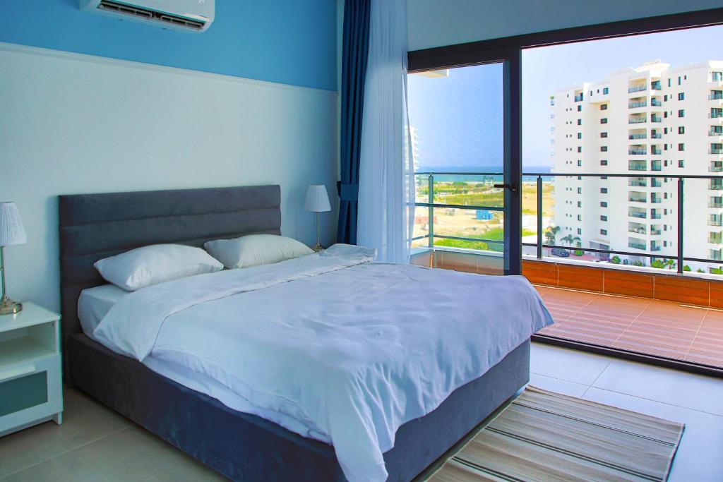 a bedroom with a large bed and a large window at Neron Family Sea View Apartment in Caesar Resort & SPA, Long Beach in Perivolia tou Trikomou